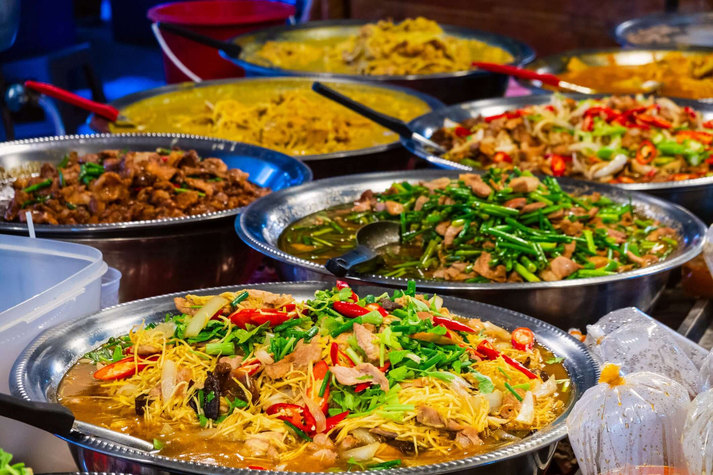 Vibrant selection of Thai street food with pad thai, green beans, and various dishes in Bangkok's market.