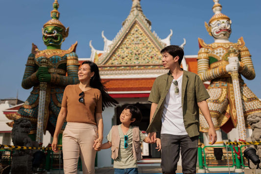 Family enjoying a cultural adventure in Bangkok, featuring colorful statues at a temple.